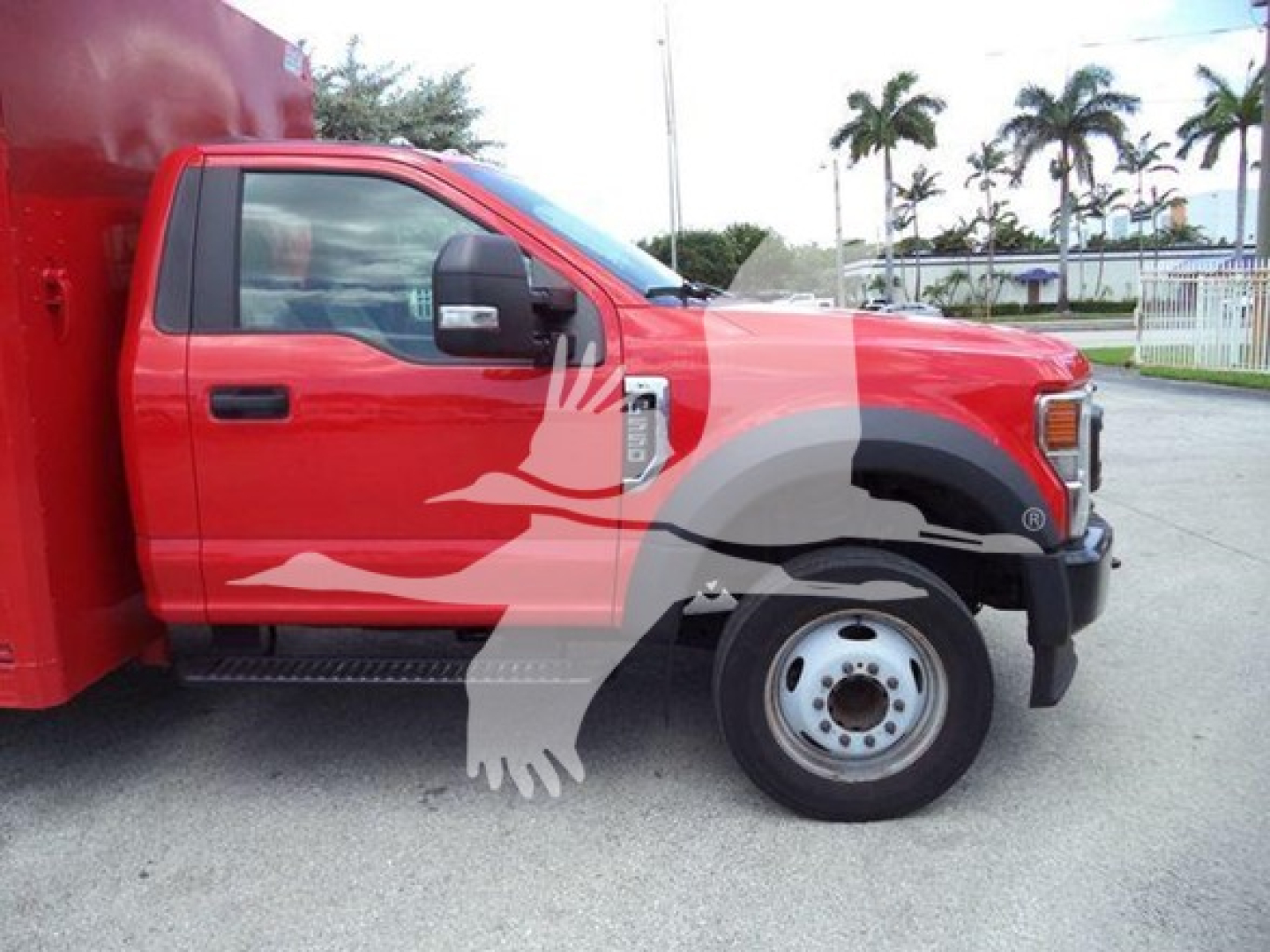 Ford F-Series truck side view showing front wheel, cab, and red beverage body. Visible text on door panel area near side mirror and grille area not legible.