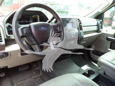 Ford F-550 interior driver area showing steering wheel with Ford emblem, center console, dashboard, and beige seats in a used truck.