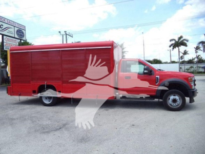 Ford F-550 truck in red with a long cargo box, side view showing the cab and dually rear wheels, used vehicle.
