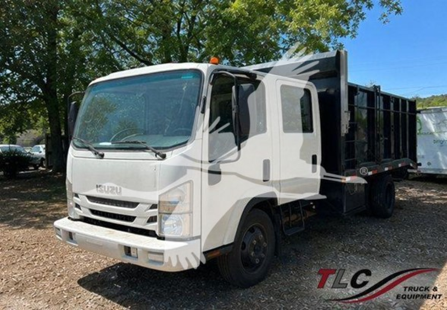 Isuzu NPR HD dump truck with white cab and black dump bed, front view showing Isuzu grille, TAC logo on windshield, TLC Truck & Equipment watermark.