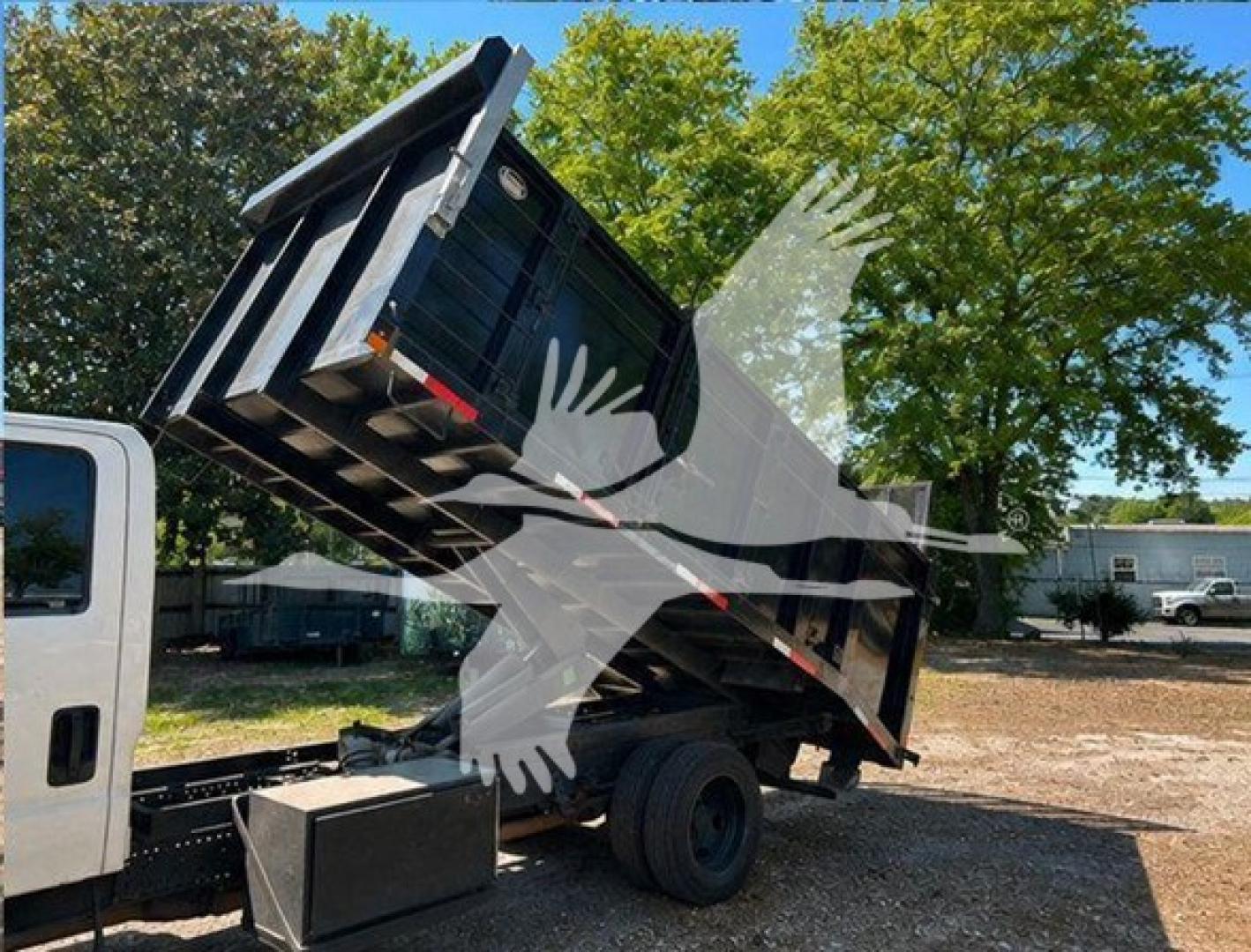 Isuzu NPR HD dump truck bed raised showing truck cab and hydraulic bed in service.