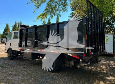 Isuzu NPR HD dump truck side view showing cargo bed and cab with black dump body and white cab.