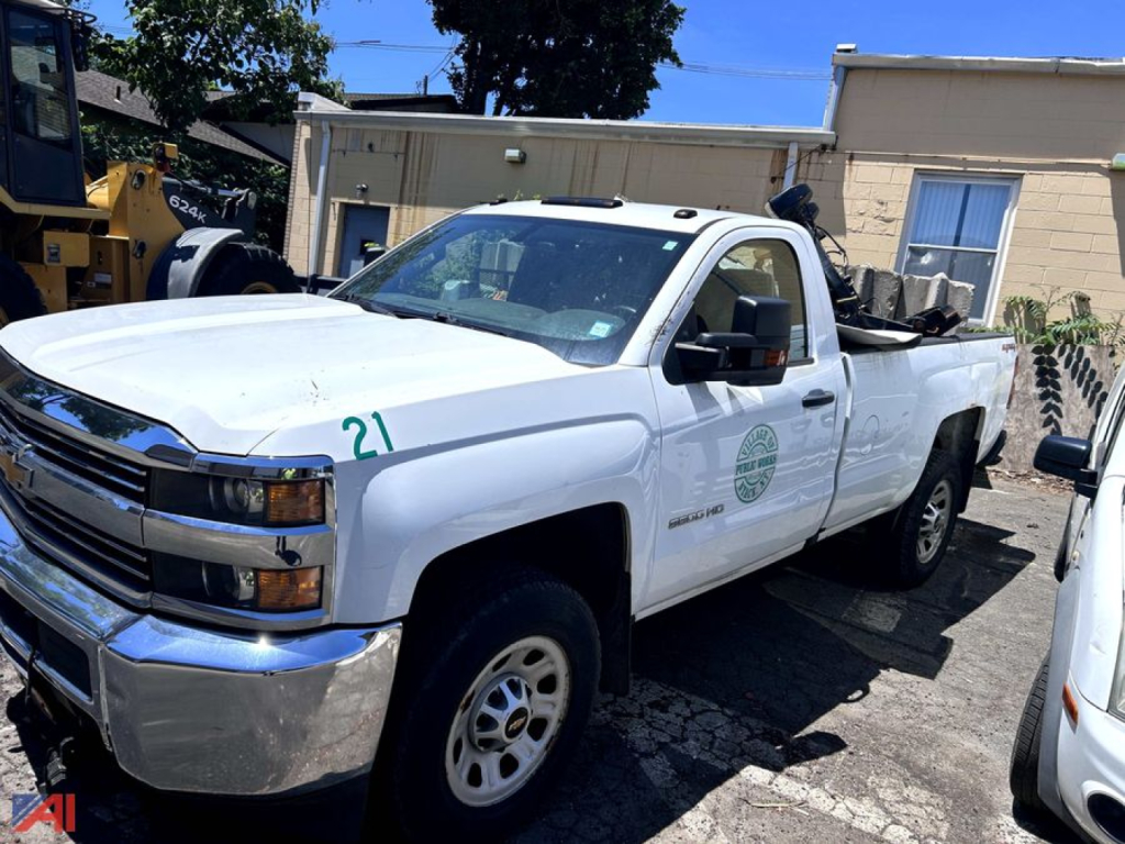 Chevrolet Silverado 3500HD pickup truck with white cab and long bed, front grille chrome, driver side view, may show markings and dealership logo on door.