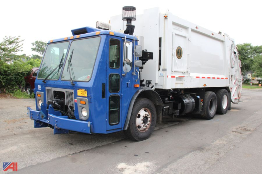 Blue Mack TerraPro cab-over engine refuse truck showing side and front with white body and pump at rear, CID badge and amber warning lights