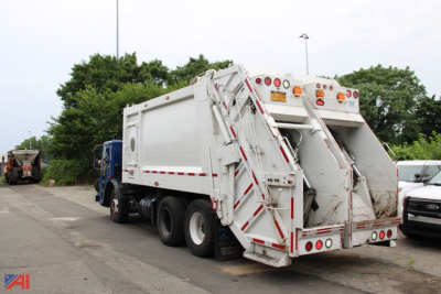 Rear view of a white Mack TerraPro cab over truck with a large dumping bed and reflective safety stripes.