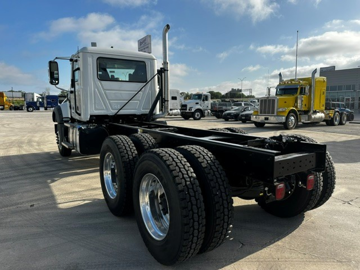 Mack GR64F dump truck chassis rear angle showing dual rear axles, silver cab, and 6x4 configuration with chrome wheels.
