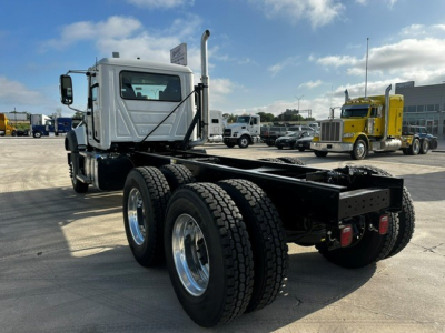 Mack GR64F dump truck chassis rear angle showing dual rear axles, silver cab, and 6x4 configuration with chrome wheels.