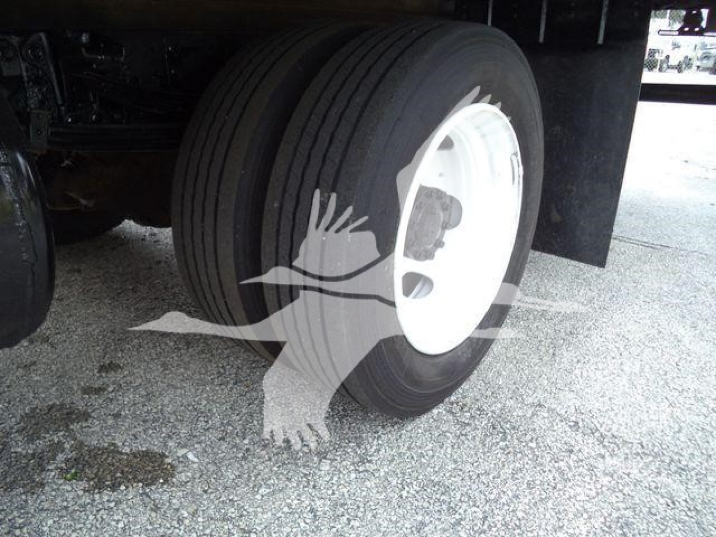 Truck wheel showing dual rear tires and white rim under cargo refrigeration vehicle
