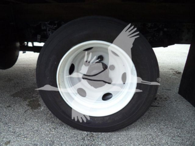 Wheel/tire and rim under a refrigerated truck showing a plain white steel wheel with black tire.