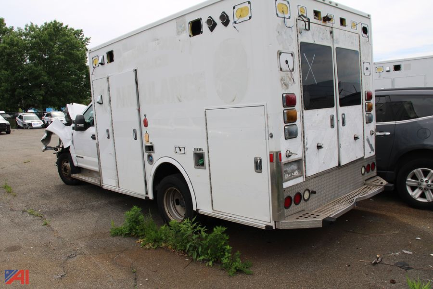 Ambulance rear and side view showing cargo compartments and rear doors, white aluminum body, multiple exterior hatch doors, ambulance equipment mounting points.