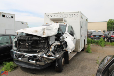 Front view of a wrecked 2017 Ford F-350 Super Duty ambulance chassis with severe front-end damage and a large box body in the back.
