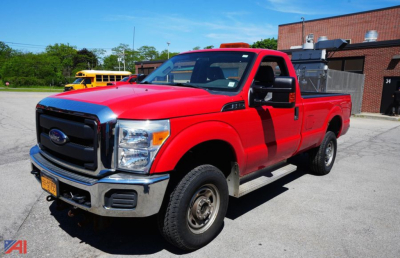 Ford F-350 XL SD dually pickup truck with plow in red, front-left view, cargo bed visible, orange emergency light bar on cab roof.
