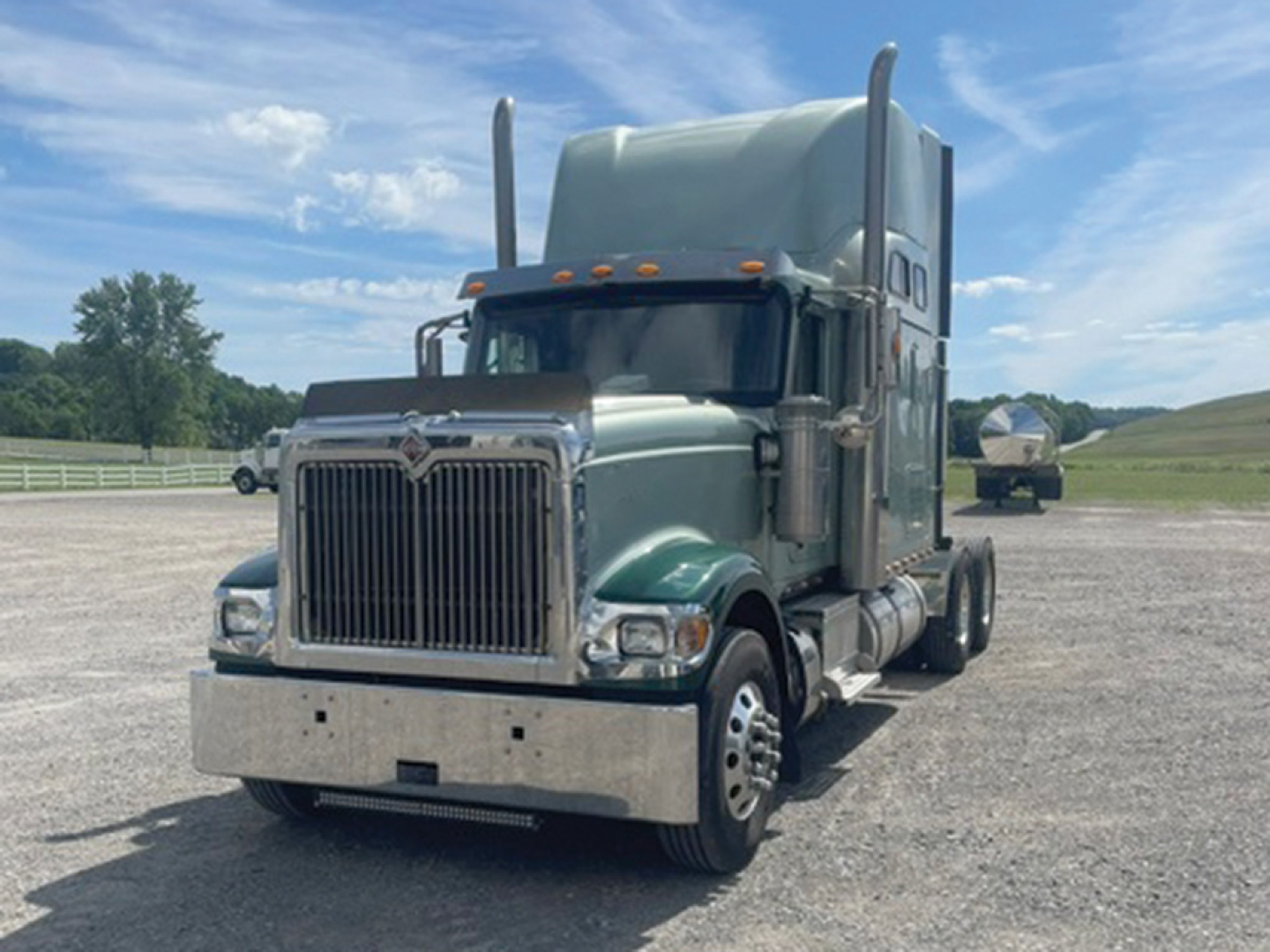 Truck front view showing 2014 International 9900i Eagle sleeper cab with tall exhaust stacks and chrome bumper.