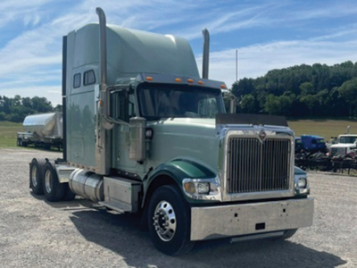 Truck cab in-service 2014 International 9900i Eagle conventional sleeper tractor with high roof, chrome grille, dual exhaust stacks, and aluminum bumper.