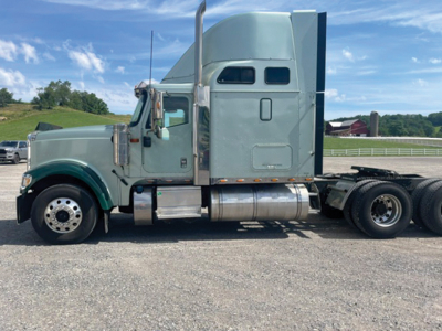 International 9900i Eagle sleeper cab tractor side view showing green/gray exterior and chrome fuel tanks.