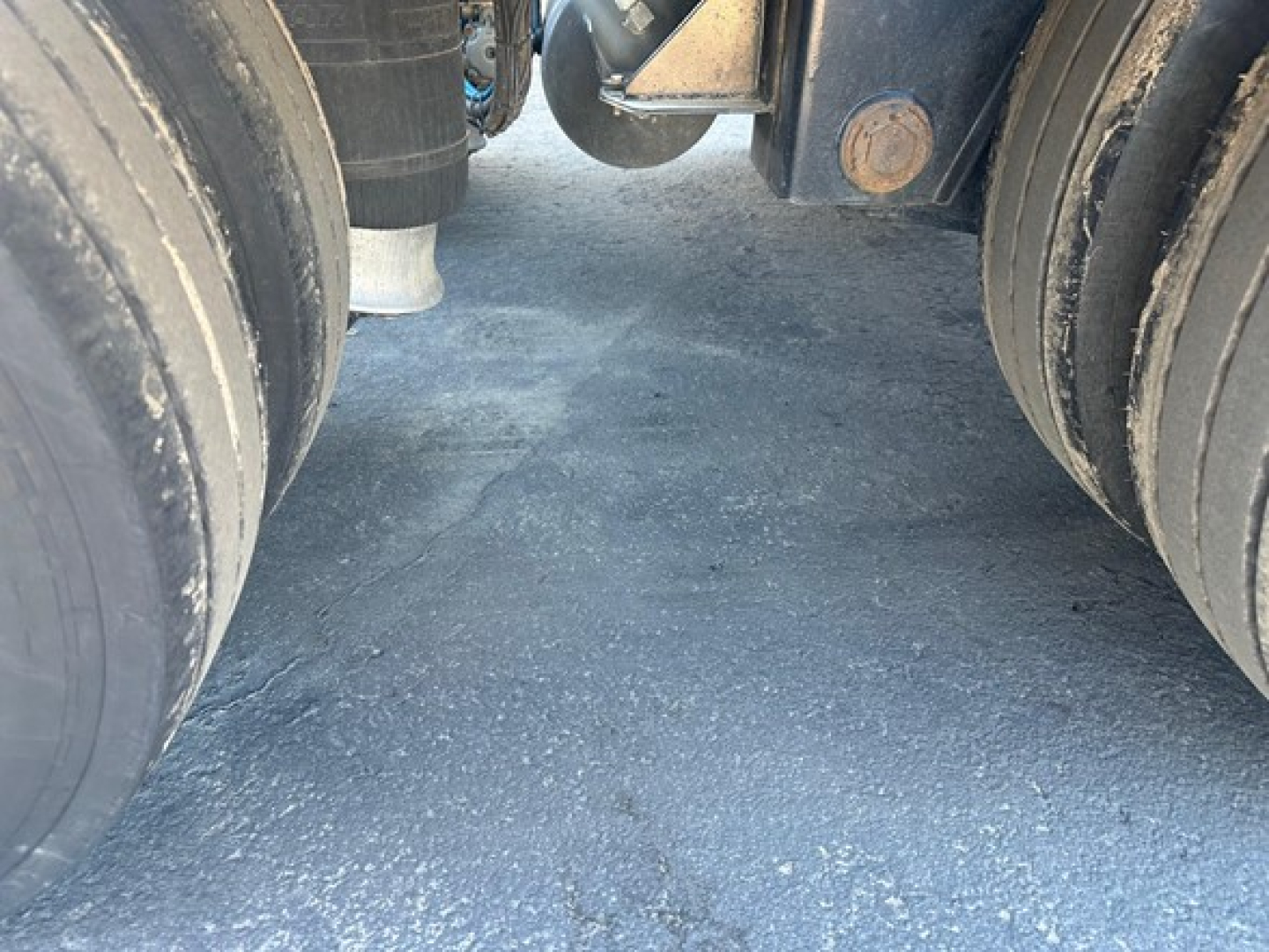 Kalyn Siebert lowboy trailer underside between dual rear axles showing tires and frame components.