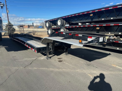 Trailer lowboy with flatbed extendable ramp showing beaver ta-pattern Kalyn Siebert branding and stacked trailers in lot.