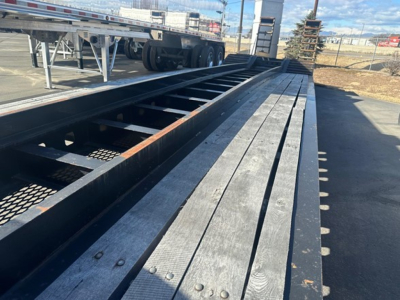 Trailer deck close-up showing long wooden planks and steel frame of a Kalyn Siebert Beaver lowboy trailer.