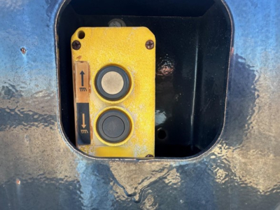 Trailer control panel with yellow switch plate showing arrows up and down inside a blue Kalyn Siebert lowboy trailer compartment.