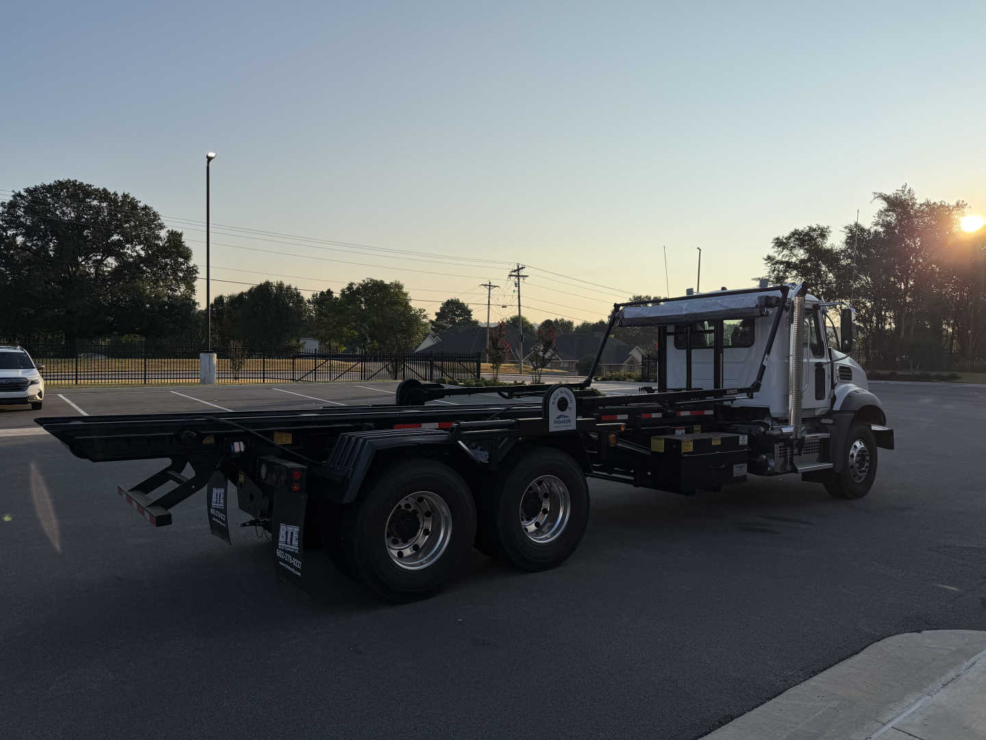 2027 Mack GR64B roll-off truck showing cab and long flatbed with multiple axles and chassis components visible.