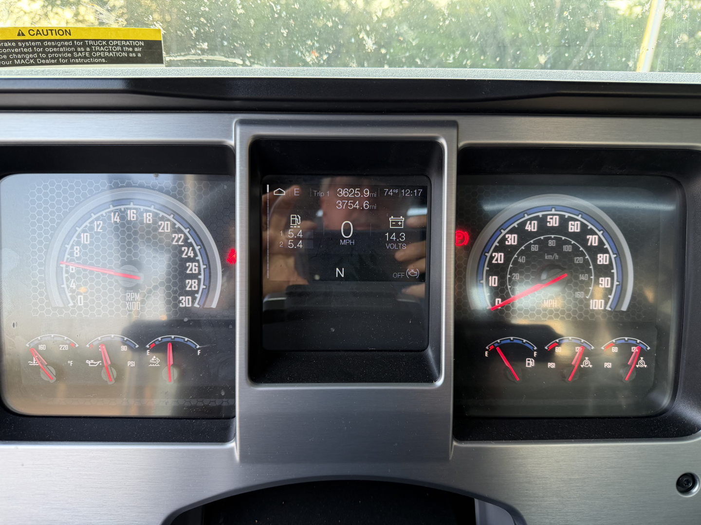 Dashboard of a 2027 Mack GR64B showing analog gauges and a central digital display with driving data.
