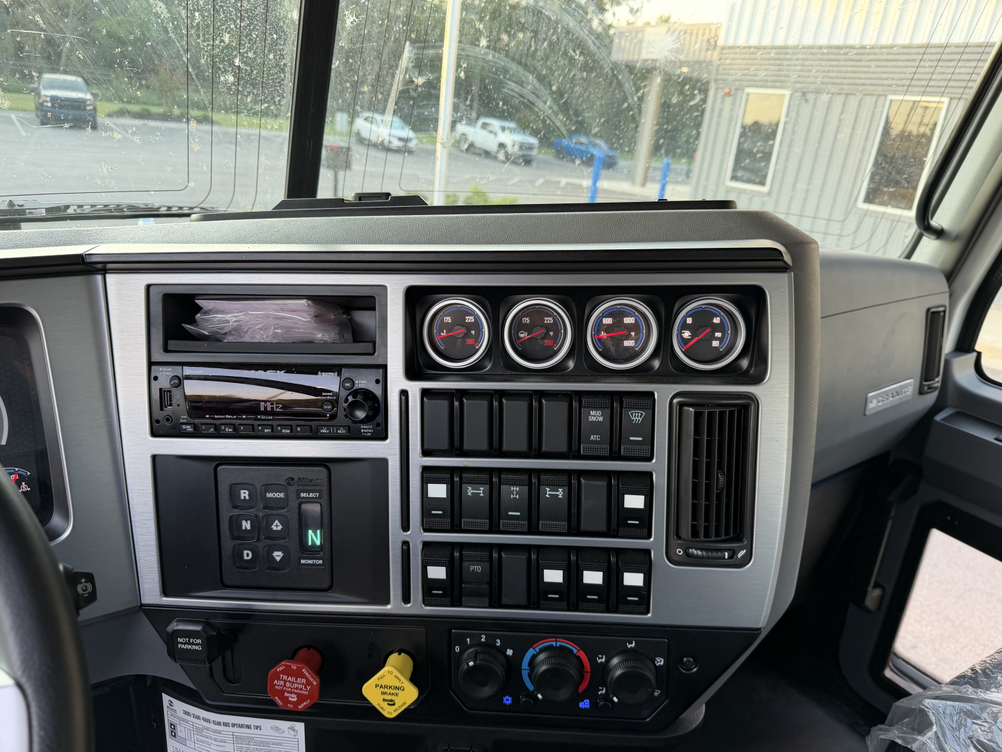 Dashboard interior of a Mack GR64B cab showing multiple gauges, switches, and control stalks; includes vehicle controls and dash layout.