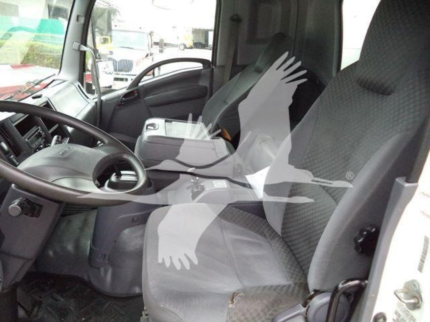 Isuzu FTR cab interior view showing driver's seat, steering wheel, and dashboard from open door.