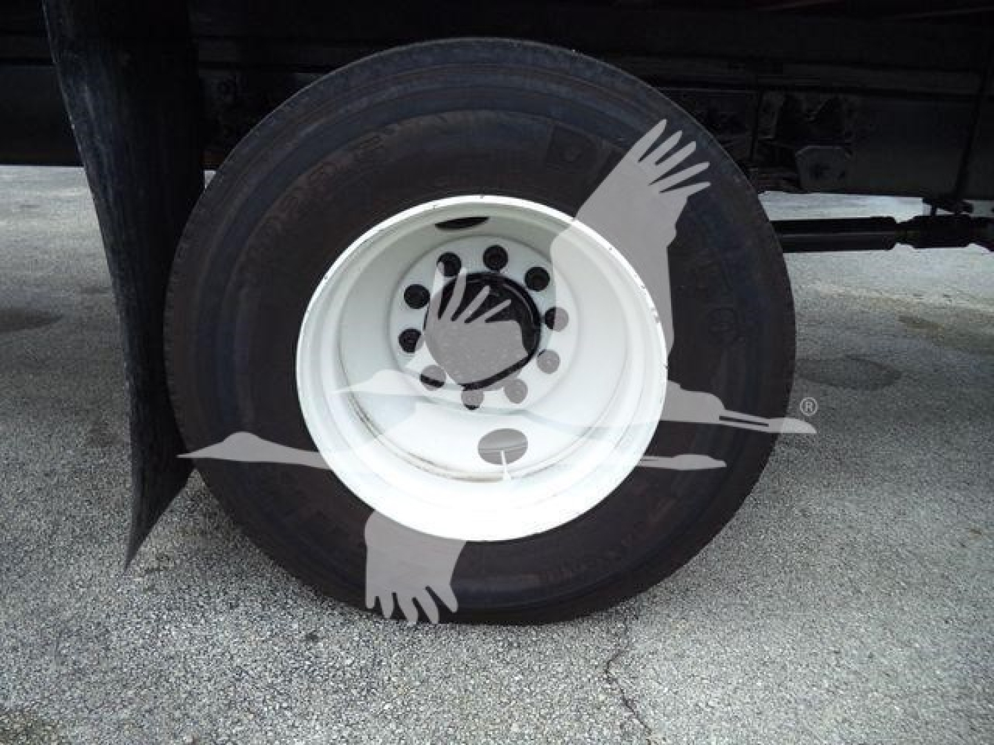 Front wheel and tire on Isuzu truck chassis showing white steel rim and black tire.