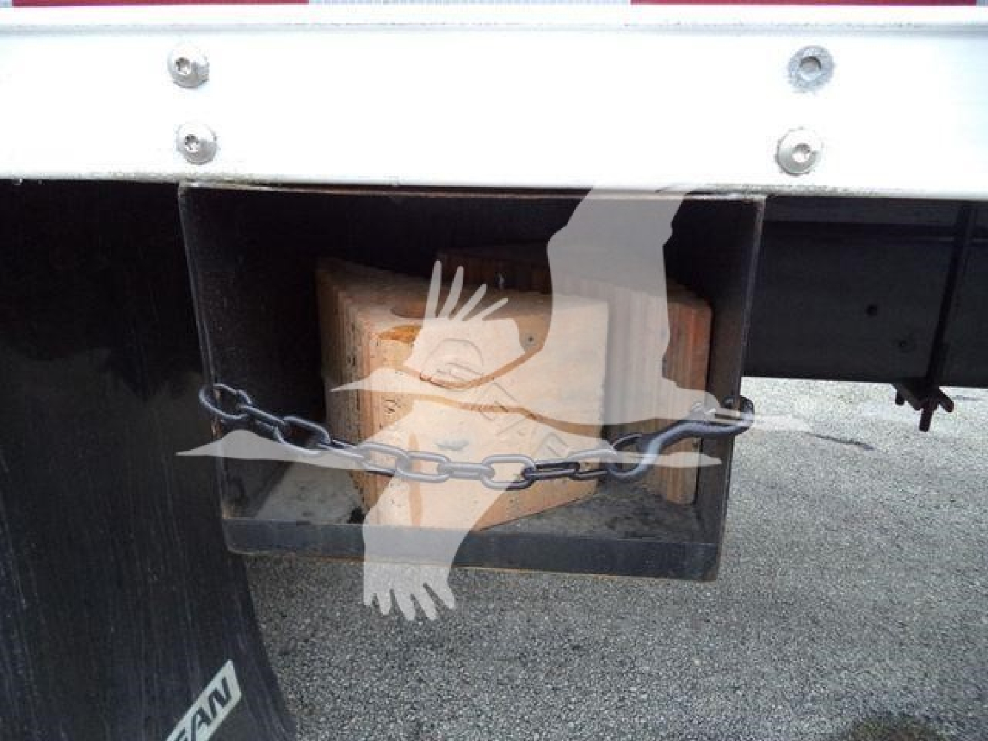 Isuzu box truck rear showing hitch/receiver area with chain and wooden block in spare well.