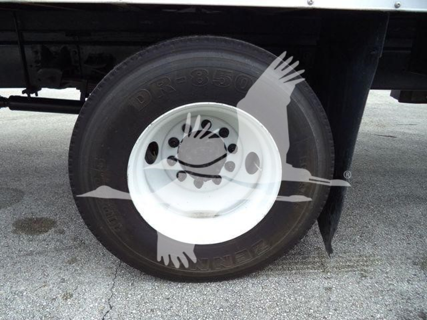 Wheel and tire on Isuzu box truck with white steel rim, partial undercarriage visible