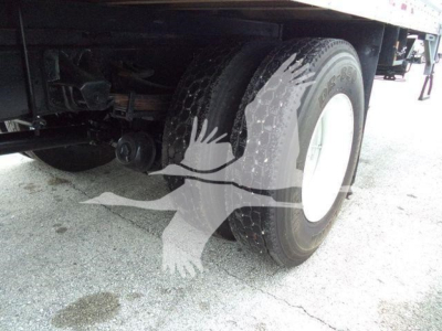 Truck wheel and undercarriage view showing rear dual tires, suspension, and part of frame.