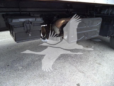Isuzu FTR underbody showing battery box on left and exhaust/radiator area on right, with a toolbox and frame visible.