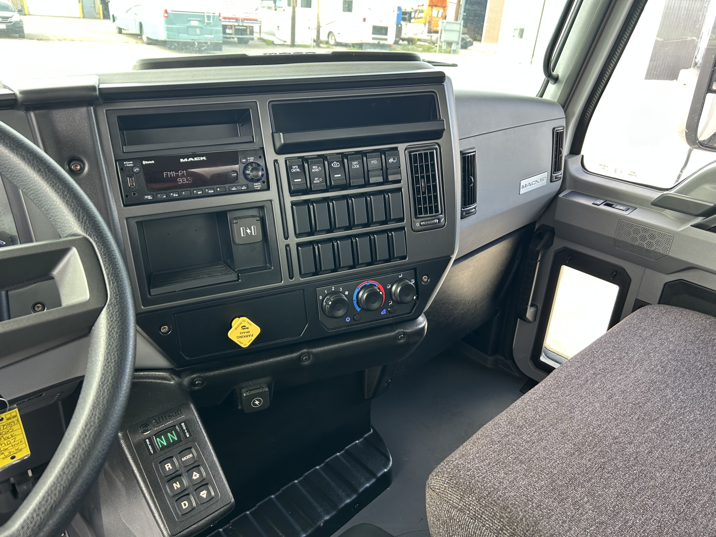 Mack MD7 truck interior dashboard and steering wheel; center console with radio, controls, and vents visible.