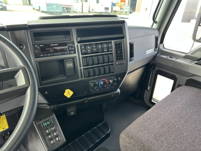 Mack MD7 truck interior dashboard and steering wheel; center console with radio, controls, and vents visible.