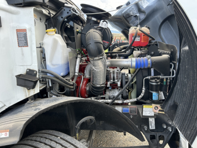 Mack MD7 engine bay showing coolant reservoir, air intake duct, hoses, and engine components.