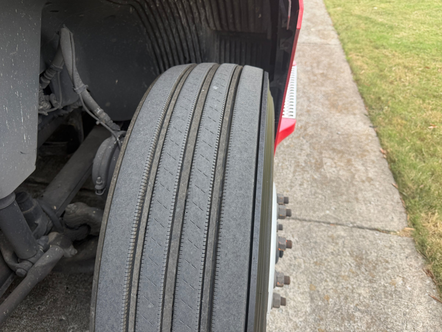 Truck wheel and front suspension view showing tire tread and lug nuts on a 2022 Volvo VNL64T760.