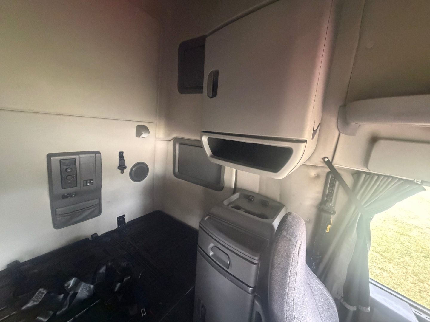 Volvo VNL interior cab area showing dashboard panel, storage compartments, and driver seat from side angle.