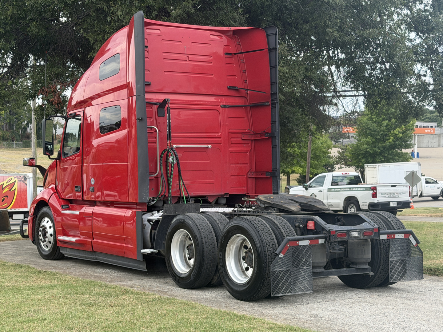Volvo VNL64T760 sleeper tractor in red showing rear view with fifth wheel, dual rear axles, and mud flaps.