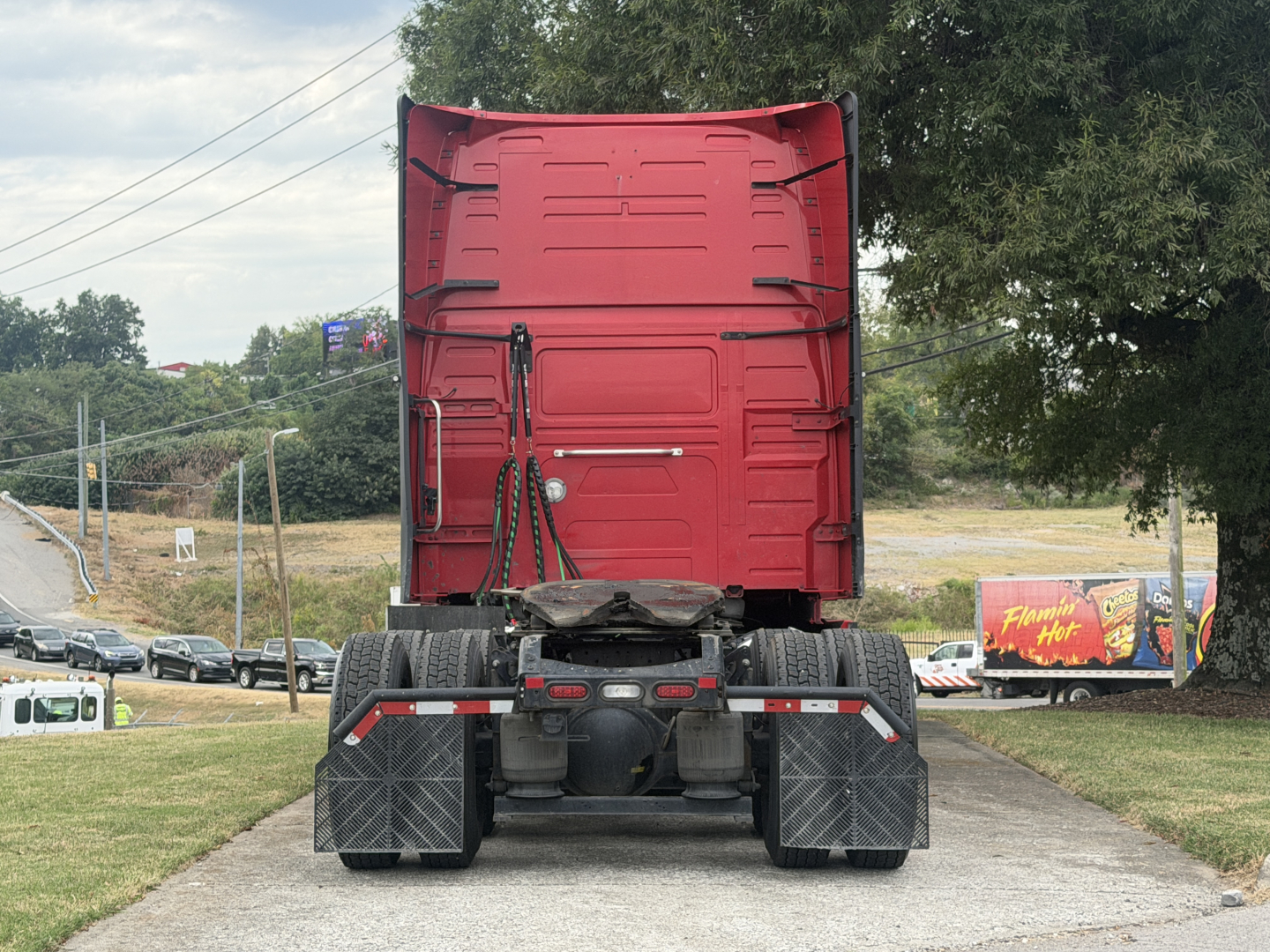 Rear view of a red Volvo VNL64T760 truck tractor showing fifth wheel, rear axles, mud flaps, and sleeper cab, no trailer attached.