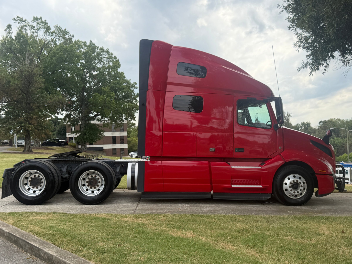 Volvo VNL64T760 tractor in side profile view with red cab and sleeper, chassis and dual rear axles visible.