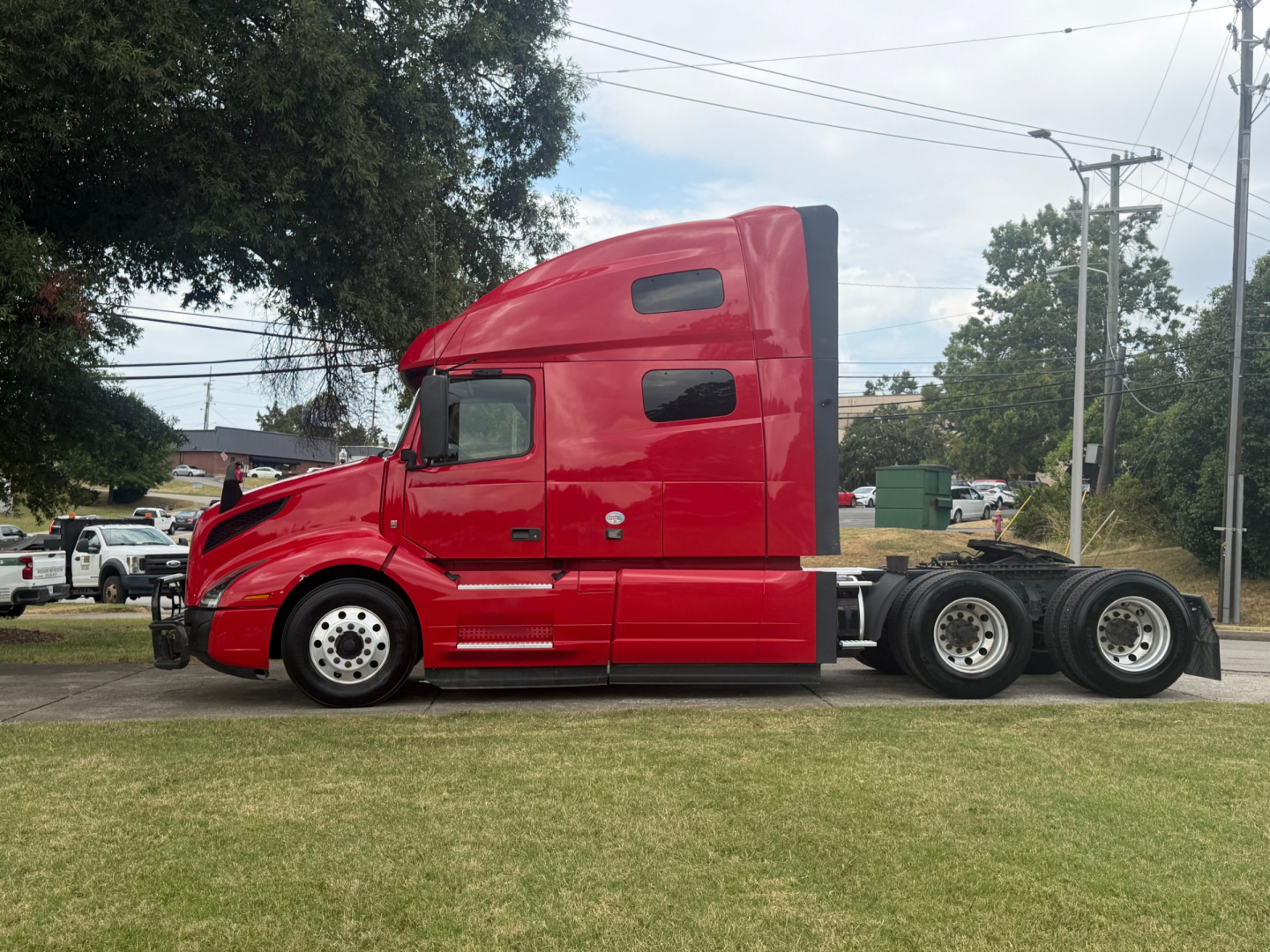 Volvo VNL64T760 truck side view showing sleeper cab and 6x4 tractor with red paint.