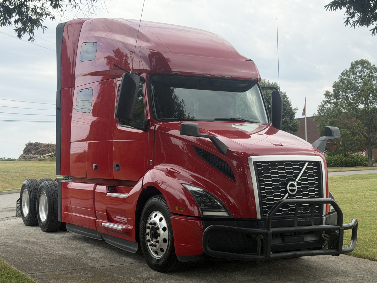 Volvo VNL64T760 sleeper tractor with large grille guard and red paint. Side shows no readable labels. Vehicle appears in a parking lot.