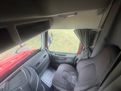 Volvo truck cab interior view with driver's seat and dashboard. Visible text includes document on seat and some control labels on the door, though legible text is minimal.