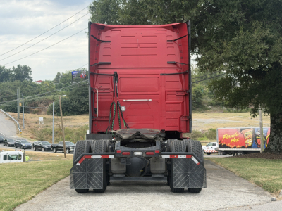 Rear view of a red Volvo VNL64T760 truck tractor showing fifth wheel, rear axles, mud flaps, and sleeper cab, no trailer attached.