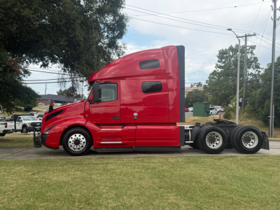 Volvo VNL64T760 truck side view showing sleeper cab and 6x4 tractor with red paint.
