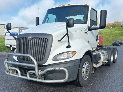 Truck shows 2019 International RH613 conventional daycab with front grille guard and dual rear axles, white cab, large side mirrors, VIN plate not visible.