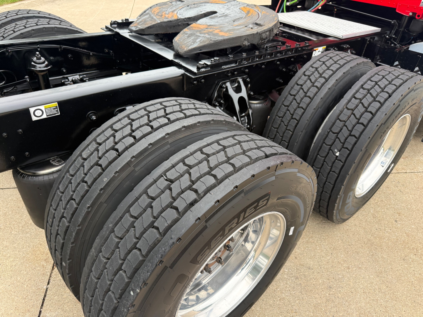Kenworth T680 chassis showing dual rear axles with five tires and rims, fuel/tank support near frame, and a visible fifth wheel mount area.