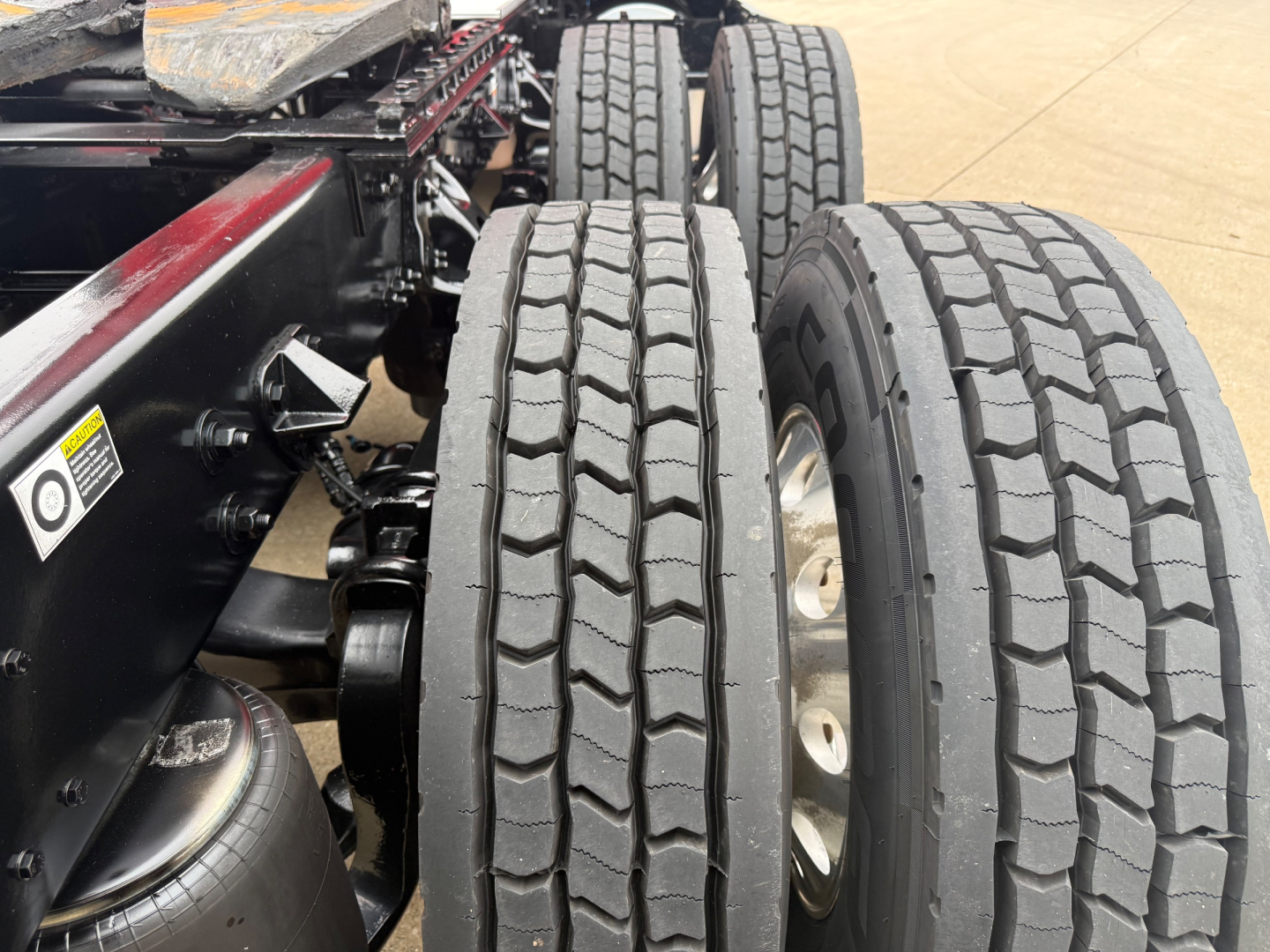 Kenworth T680 truck chassis showing dual rear axles and tire tread pattern, viewed from side with fuel tank and frame components visible.