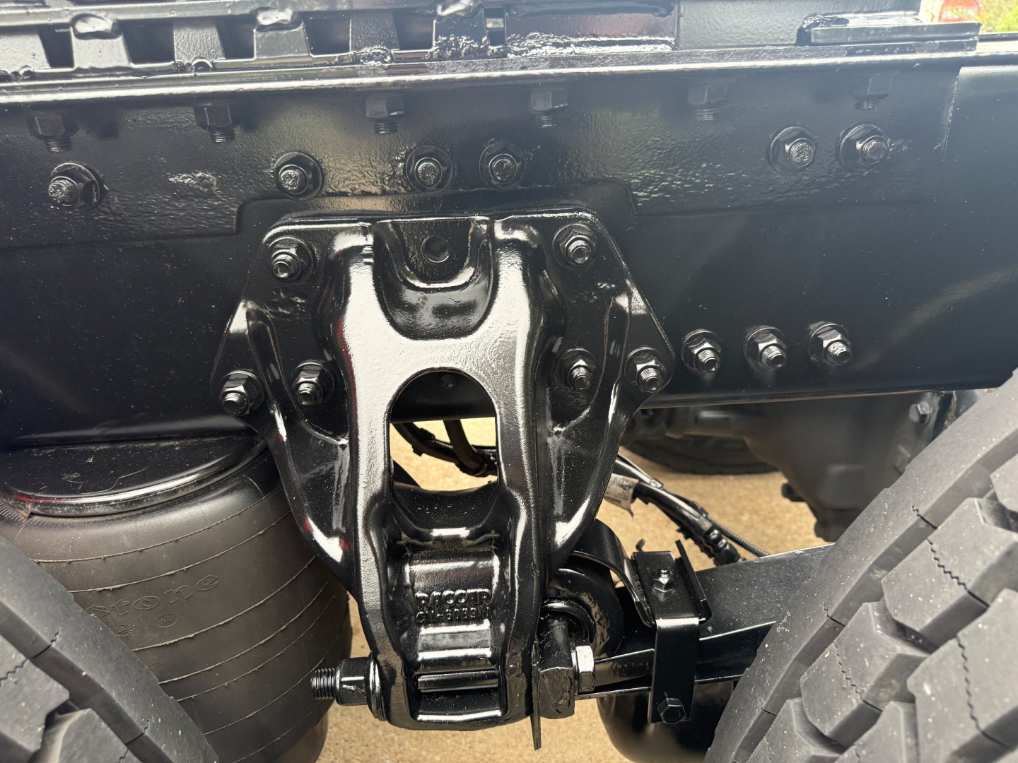 Truck rear view showing fifth-wheel hitch assembly and frame of a Kenworth T680 undercarriage.