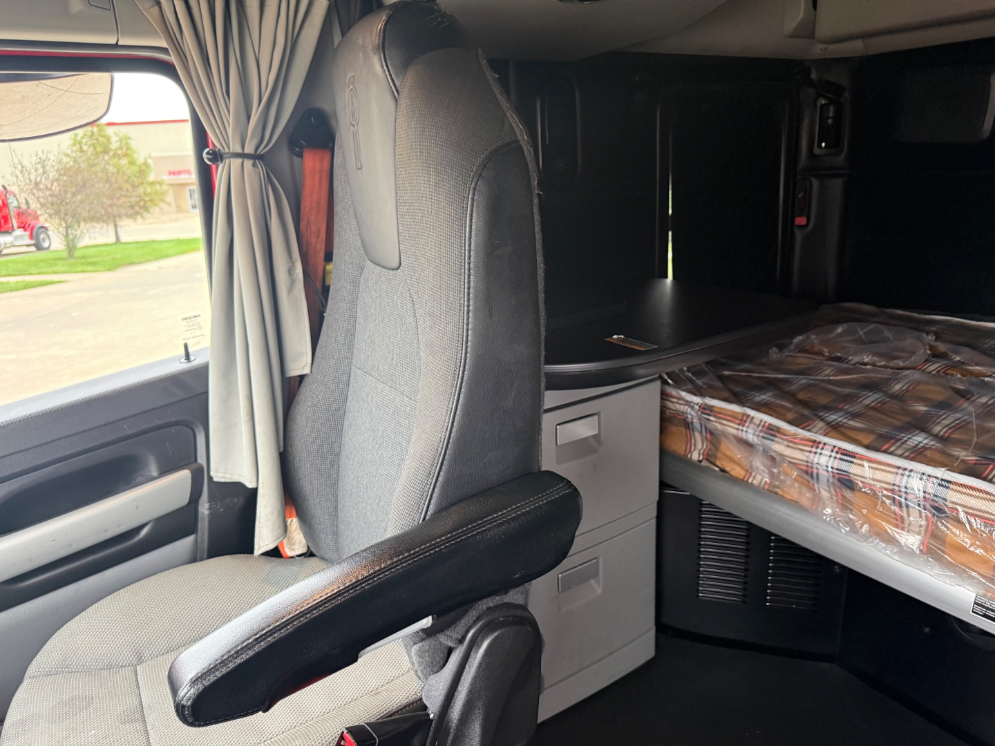 Kenworth T680 sleeper cab interior showing driver's seat, overhead cabin with bed, and storage drawers.